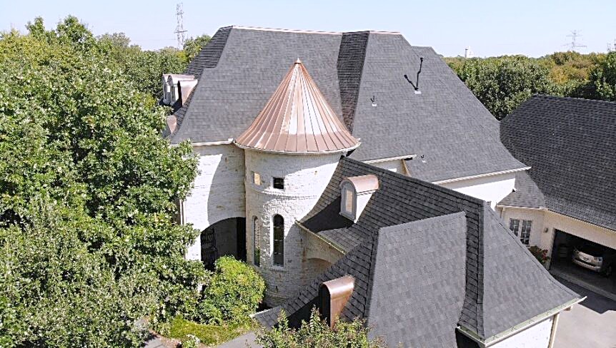 Copper turret roof and surrounding shingle planes on a large custom home