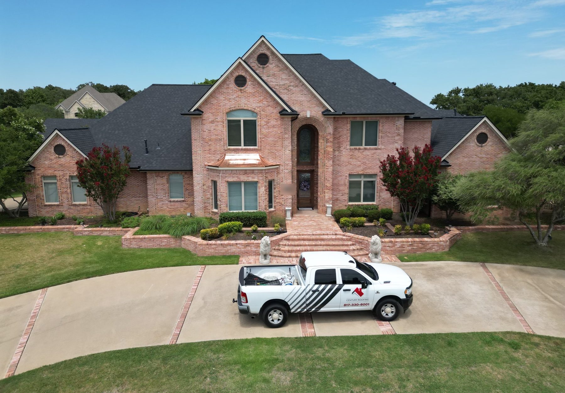 A two-story brick home with a new dark shingle roof and a Century Roofing truck in the driveway