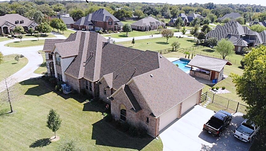 Aerial view over a North Texas neighborhood with a newly finished roof in the foreground