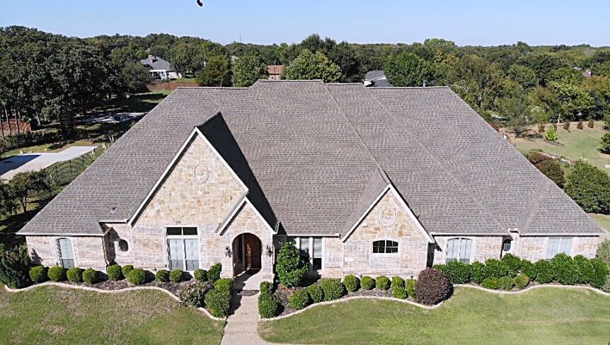 Wide aerial of a stone home showing the full roof and every plane